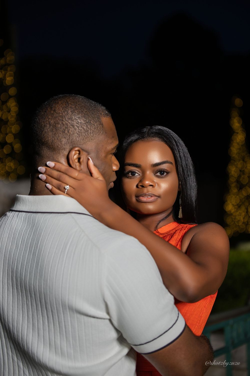 A tender moment captured at night with glowing lights in the background.