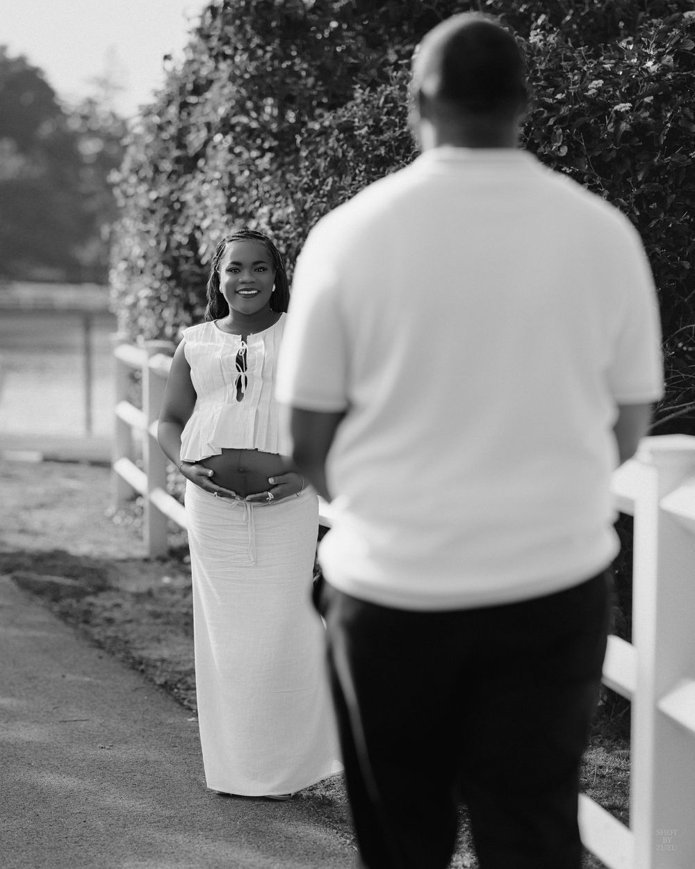 Black and white photo series showing a couple in white and black attire posing together outdoors by a fence.