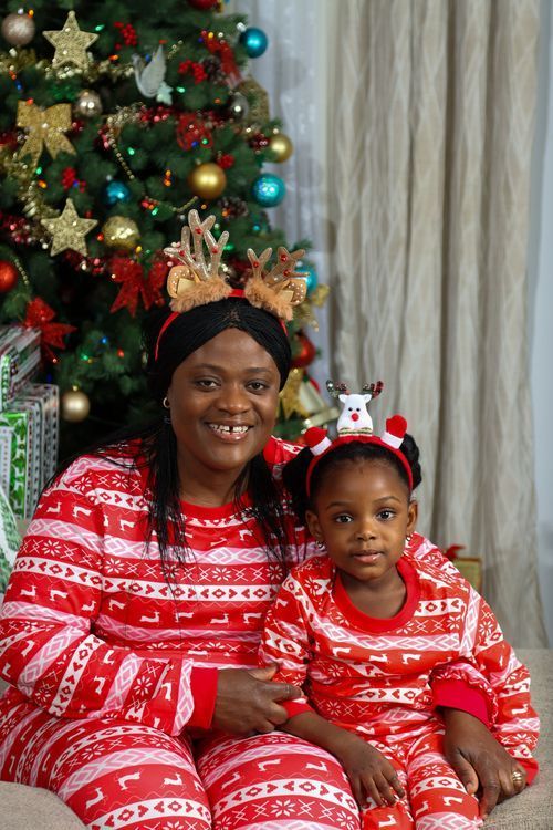Family wearing matching red and white Christmas pajamas by decorated tree.