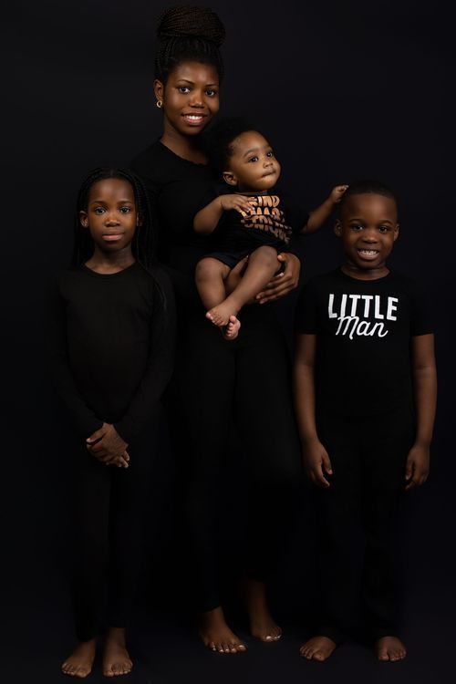 Modern family portrait with everyone wearing black against dark background.