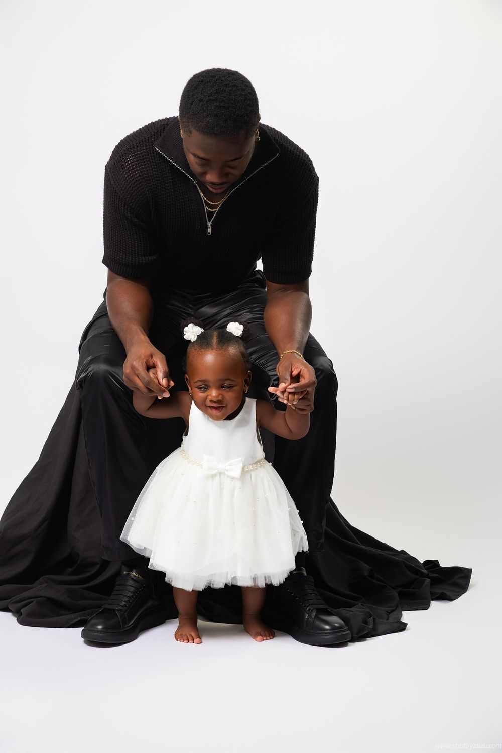 Studio portrait showing an intimate moment between parent and child in contrasting black and white outfits.