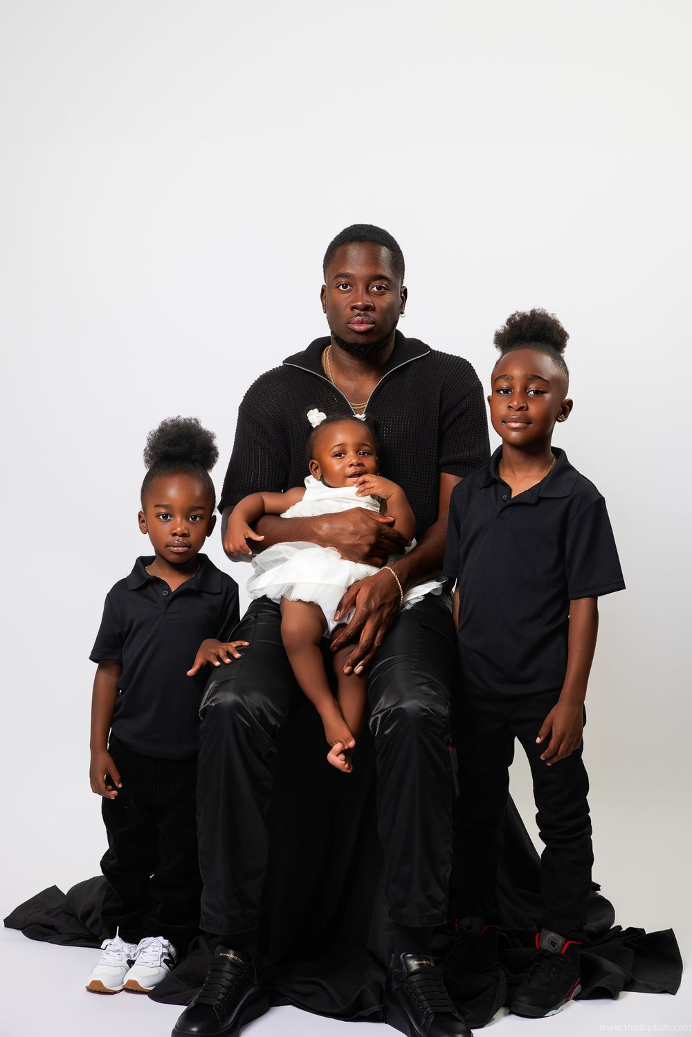 Studio family portrait showing coordinated black and white outfits against white background.