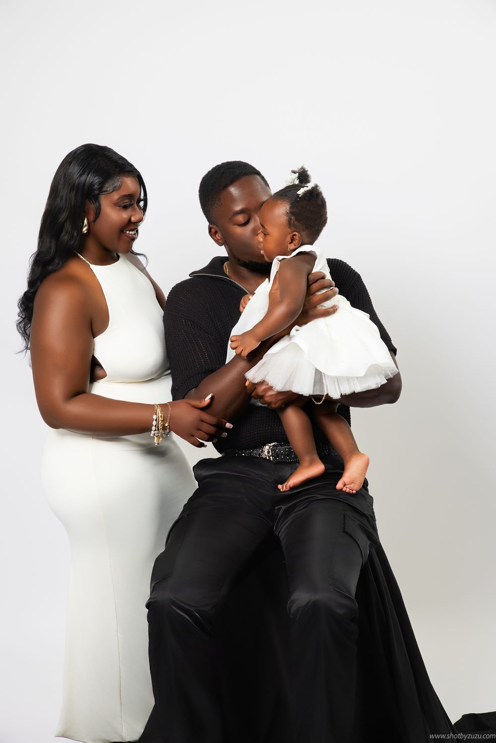 Candid family studio photo showing tender moment between family members in black and white attire.