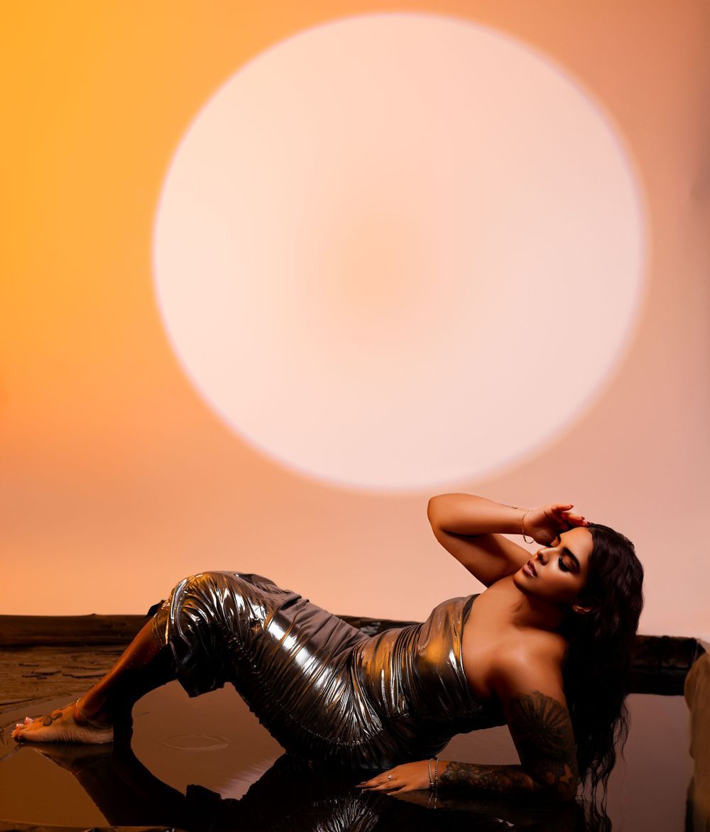 Artistic portrait with metallic dress against orange circular backdrop.