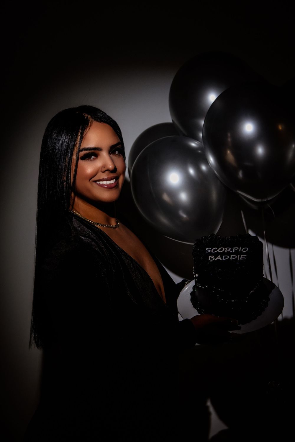 Glamorous portrait with black balloons against dark background in evening wear.