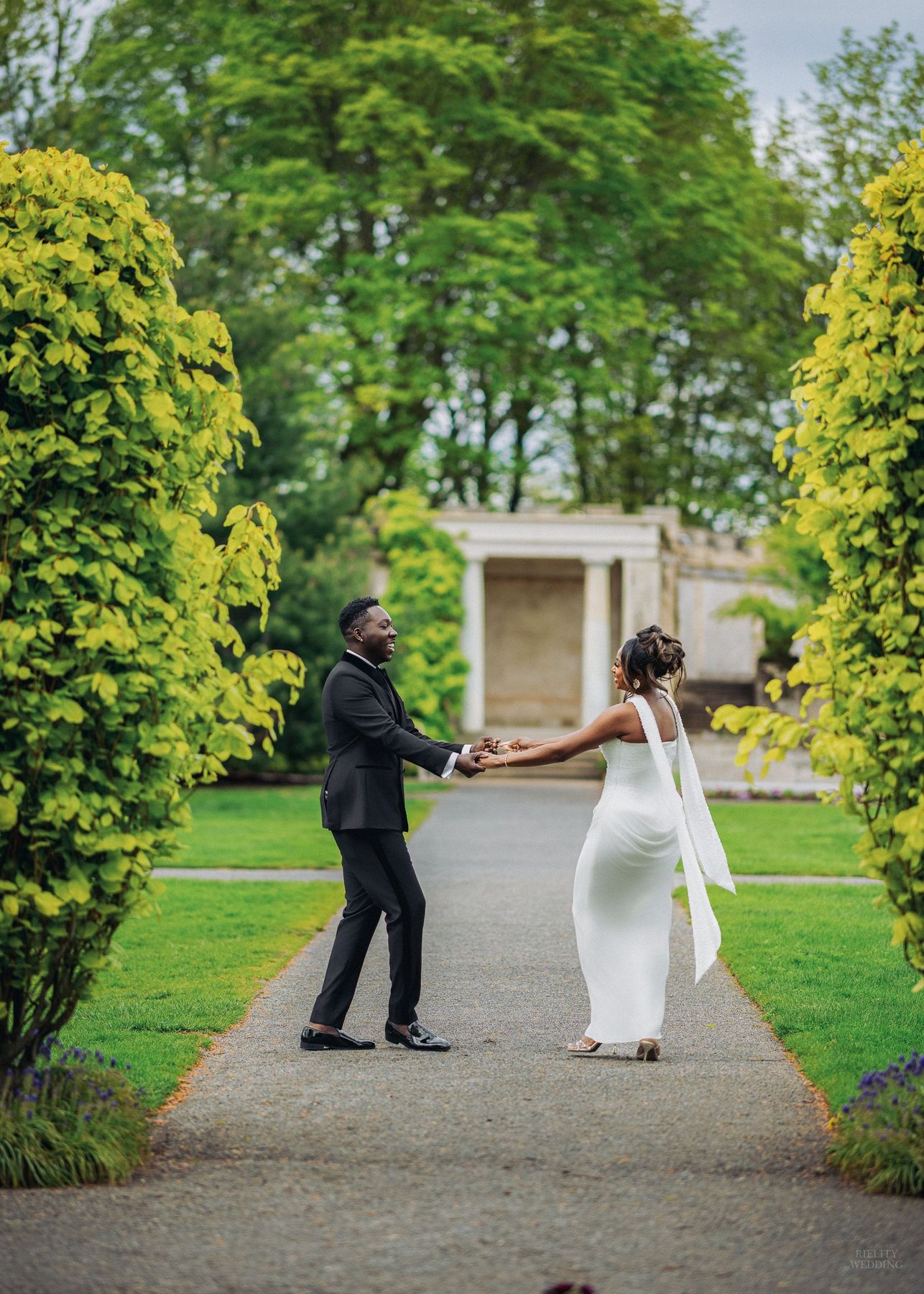 Couple in white sharing a kiss while holding a blue and white bouquet