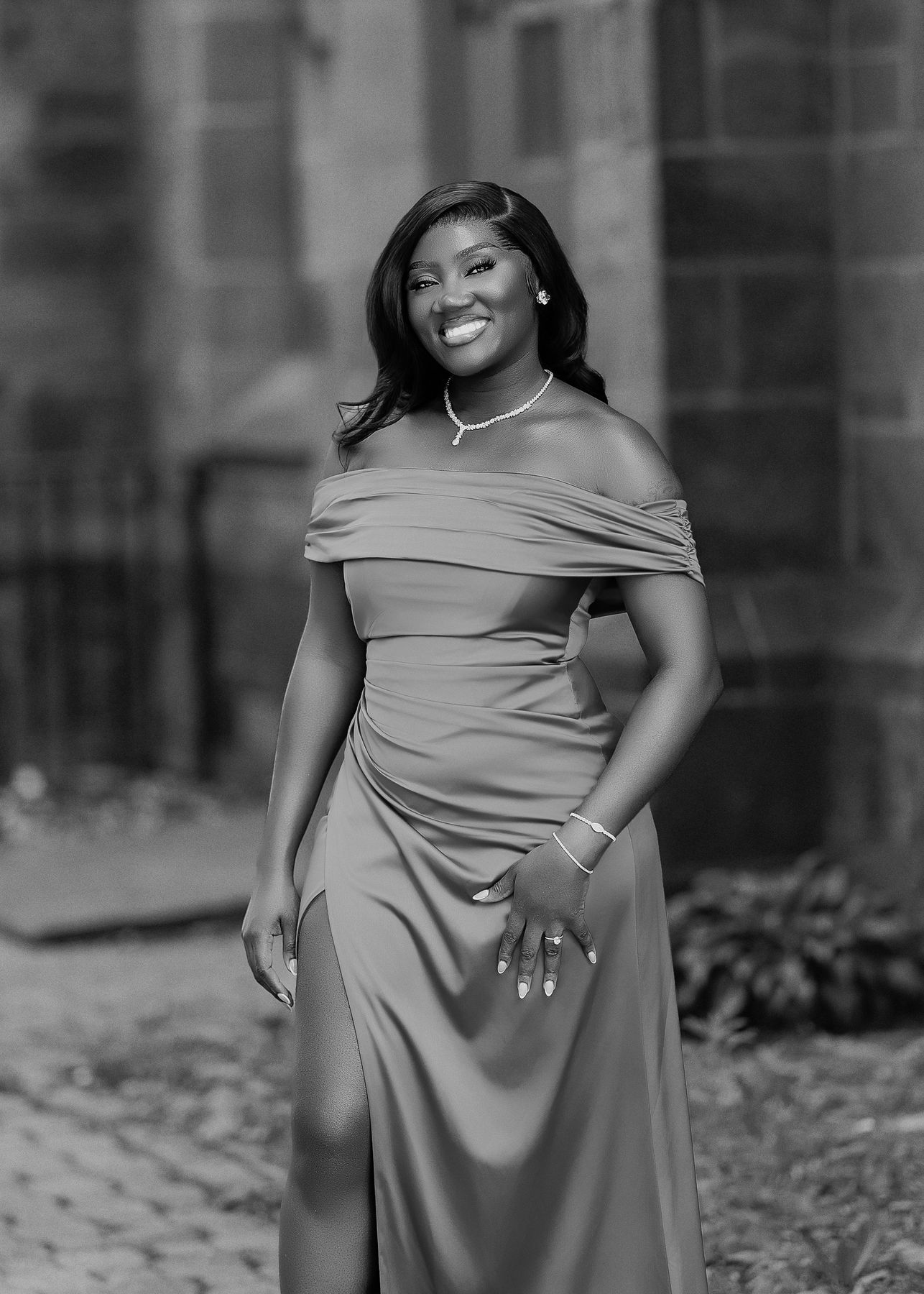 Black and white portrait of Maame Yaa smiling in an off-shoulder gown