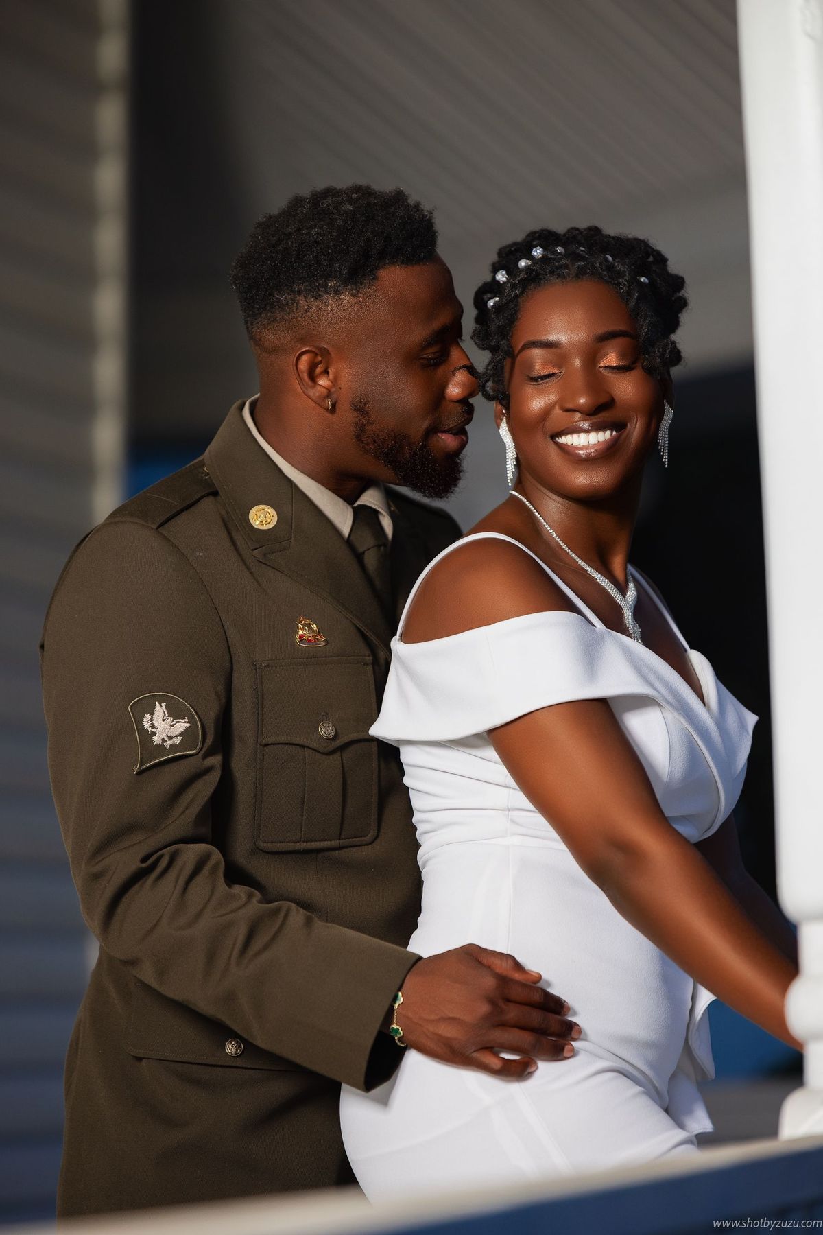 Military serviceman and bride share an intimate moment in formal wedding attire against a classic column backdrop.
